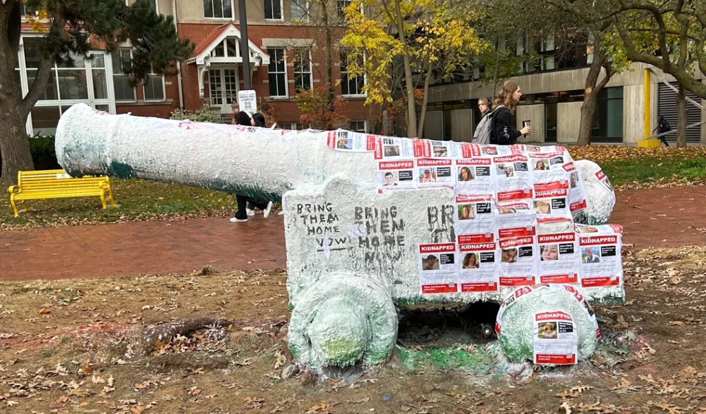 Cannon statue on the University of Guelph campus covered with posters reading “KIDNAPPED” and the message “Bring them home now.”
