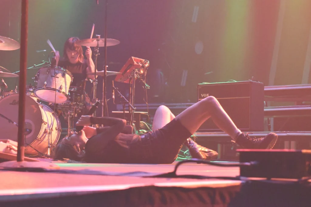 Singer lies on the stage floor while singing into a microphone during a live performance.