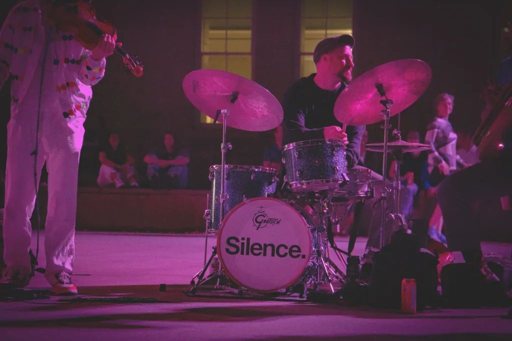 Drummer performs on a Gretsch drum kit with “Silence.” written on the bass drum during a jazz set.