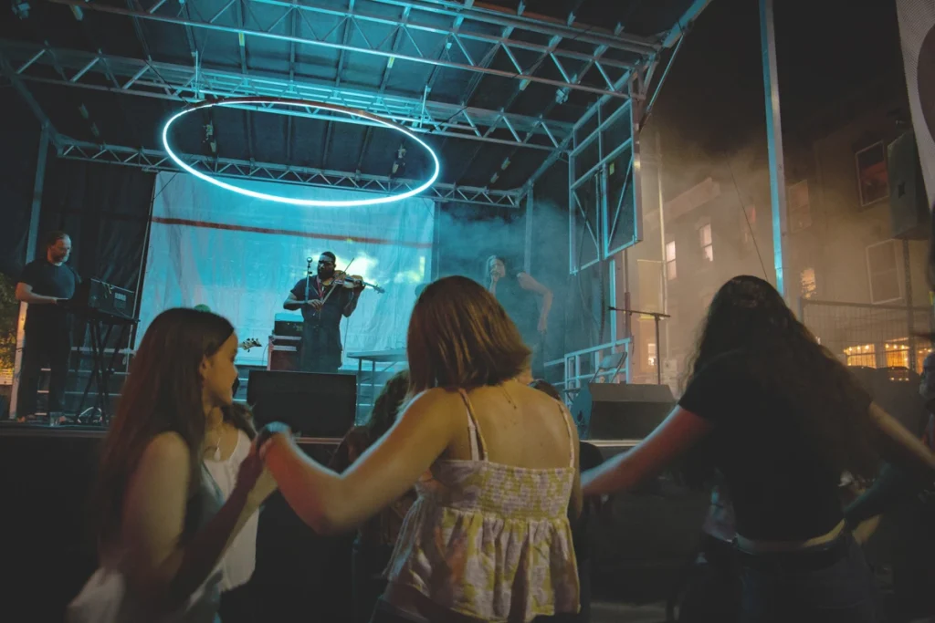 Audience members dance in front of a stage during a live outdoor jazz performance.