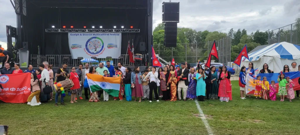 Participants carrying flags from different countries gather in front of a stage during the Guelph and District Multicultural Festival.